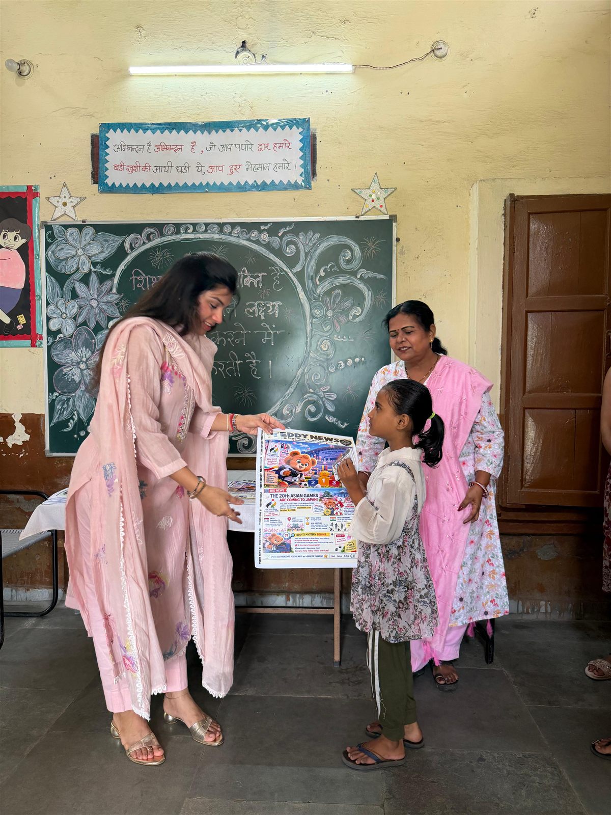 A Teddy News team member handing a newspaper to a young student
